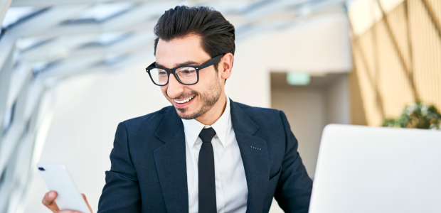 smiling businessman looking at cell phone at desk 2023 11 27 05 15 33 utc 1